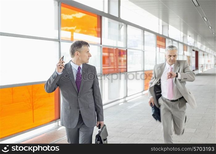 Middle aged businessman looking at colleague running in railroad station