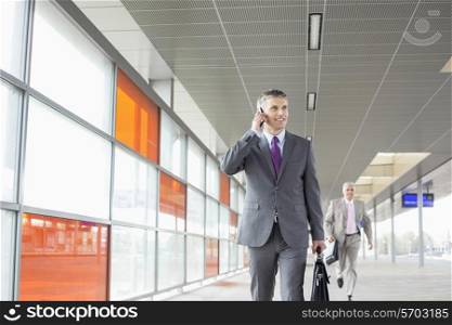 Middle aged businessman on call while walking in railroad station
