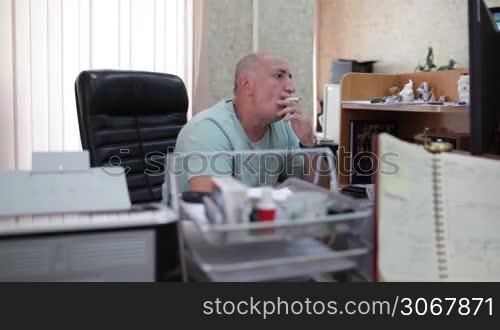Middle-aged businessman smoking and working in the office