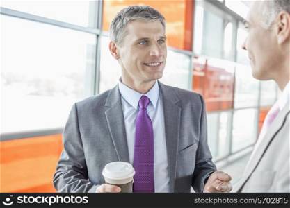 Middle aged businessman talking with male colleague in railroad station
