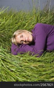 Middle-aged Caucasian woman lying on side in grass.