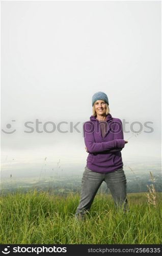 Middle-aged Caucasian woman smiling standing alone in field.