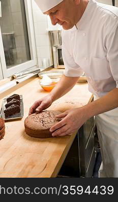 Middle aged cook placing chocolate cake in hotel&acute;s kitchen