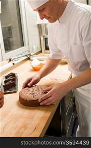 Middle aged cook placing chocolate cake in hotel&acute;s kitchen