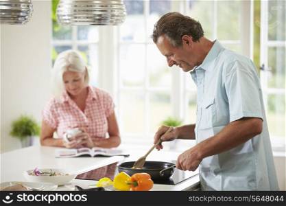 Middle Aged Couple Cooking Meal In Kitchen Together