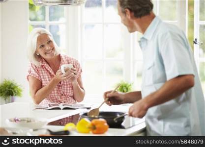 Middle Aged Couple Cooking Meal In Kitchen Together