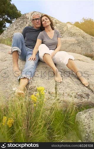 Middle aged couple, cuddling on rocks