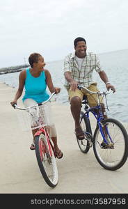 Middle-aged couple cycling at promenade
