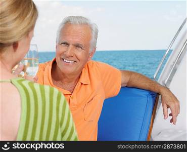 Middle-aged couple drinking wine on yacht