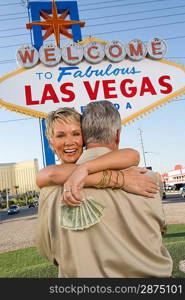 Middle-aged couple embracing in front of Welcome to Las Vegas sign