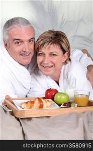 middle-aged couple having breakfast in bed