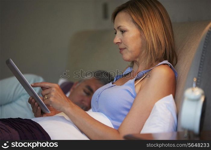 Middle Aged Couple In Bed With Woman Using Tablet Computer