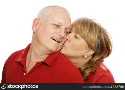 Middle aged couple isolated on white. Wife is kissing husband on the cheek.