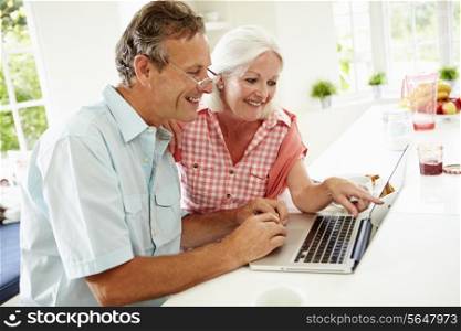 Middle Aged Couple Looking At Laptop Over Breakfast