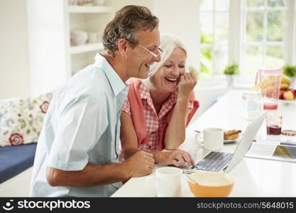 Middle Aged Couple Looking At Laptop Over Breakfast
