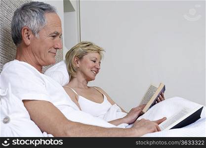 Middle-aged couple reading books in bed
