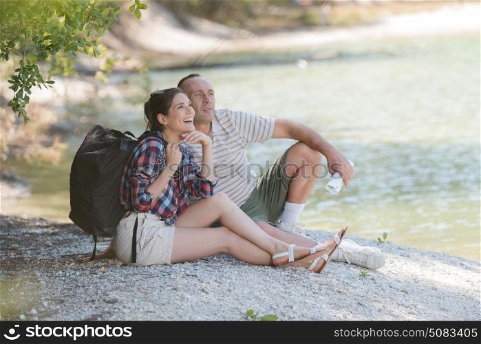 middle aged couple resting on the river bank