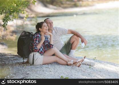 middle aged couple resting on the river bank