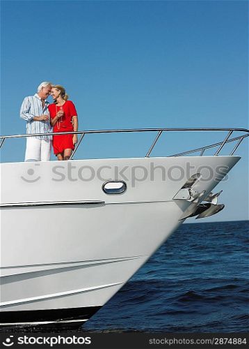 Middle-aged couple standing in bow of yacht
