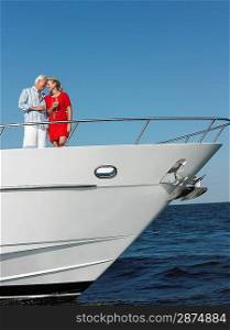 Middle-aged couple standing in bow of yacht
