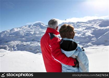 Middle-aged couple stood on secluded snowy mountain
