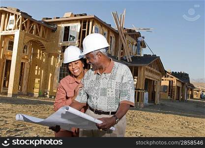 Middle-aged couple watching blueprints at construction site