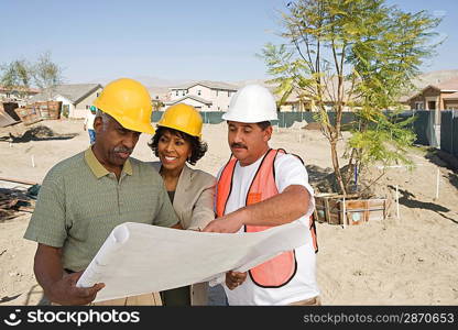 Middle-aged couple watching blueprints with surveyor