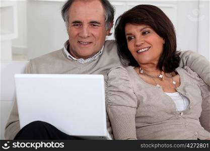 Middle-aged couple with laptop sat on sofa