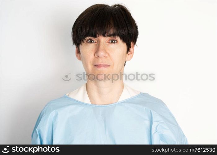 Middle-aged doctor putting on a protective gown before seeing her patient.. Middle-aged doctor putting on a protective gown