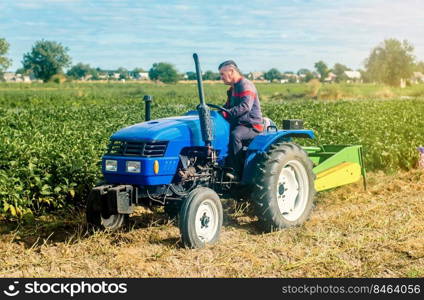 Middle-aged farmer on a tractor. Work on agricultural machinery on the field. Harvest potatoes. Farm and small business. Support and subsidies. Concessional lending and loans.