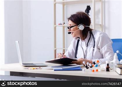 Middle-aged female doctor in telemedicine concept 
