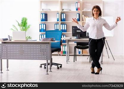 Middle-aged female employee doing exercises in the office 