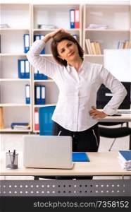 Middle-aged female employee doing exercises in the office