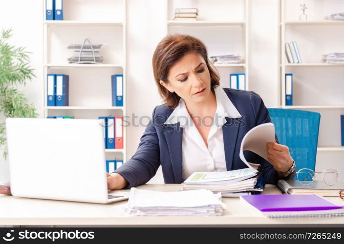 Middle-aged female employee sitting at the office  