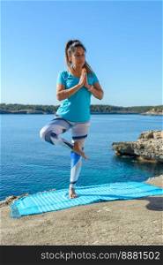 middle-aged fitness woman outdoors in front of the sea does yoga stretching exercises.. middle-aged fitness woman outdoors in front of the sea does yoga stretching exercises