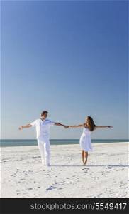 Middle aged happy man and woman romantic couple in white clothes dancing on a deserted tropical beach with bright clear blue sky