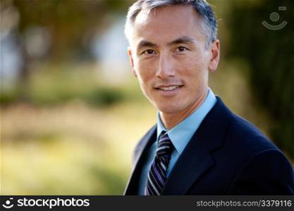 Middle aged male businessman in suit and tie standing outside. Horizontally framed shot.