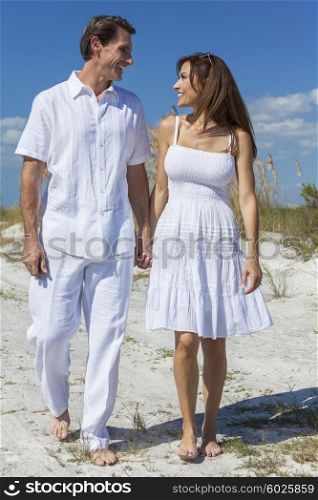 Middle aged man and woman romantic couple in white clothes walking on a deserted tropical beach with bright clear blue sky