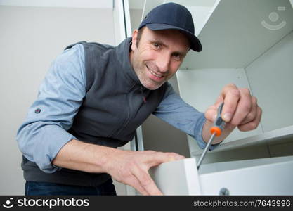 middle-aged man assembling a furniture at home