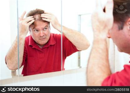 Middle aged man checking for thinning hair in the mirror.