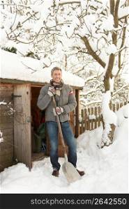 Middle Aged Man Clearing Snow From Path To Wooden Store