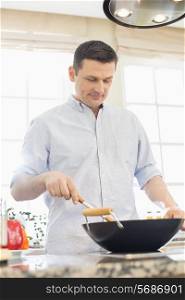 Middle-aged man cooking in kitchen