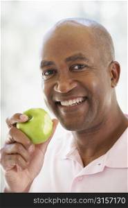 Middle Aged Man Eating Green Apple And Smiling At The Camera