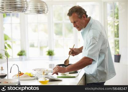 Middle Aged Man Following Recipe On Digital Tablet