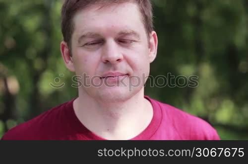 Middle-aged man looking to the camera in the park. Close up portrait.