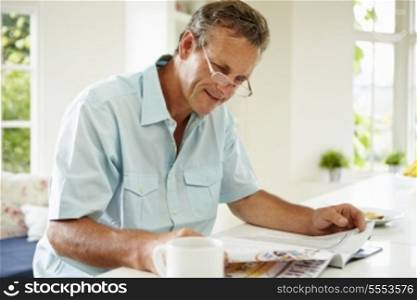 Middle Aged Man Reading Magazine Over Breakfast