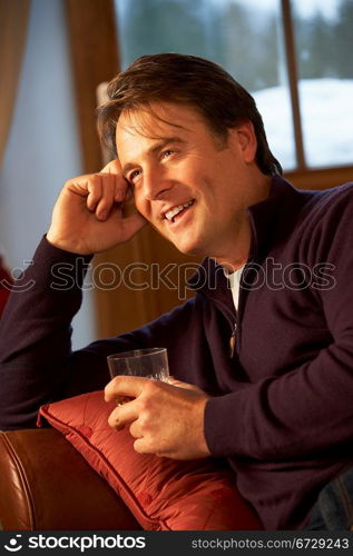 Middle Aged Man Relaxing Sitting On Sofa Drinking Whisky