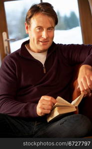 Middle Aged Man Relaxing With Book Sitting On Sofa