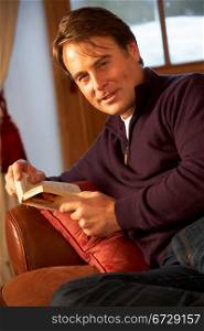 Middle Aged Man Relaxing With Book Sitting On Sofa