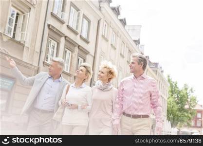 Middle-aged man showing something to friends while walking in city